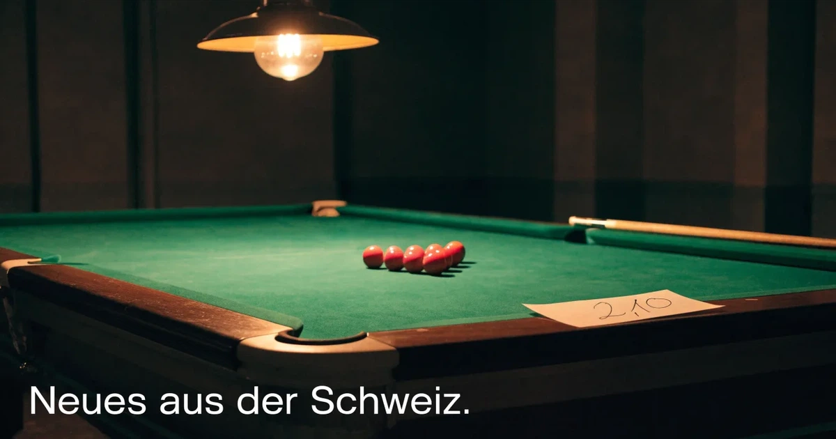 Ein Snookertisch mit grünem Tuch und einem Dreieck aus roten Kugeln unter einer tief hängenden Lampe in einer leeren Halle.