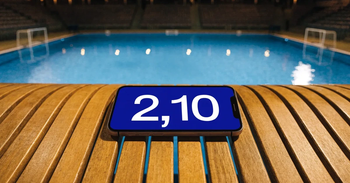 Ein Wasserballbecken am Abend mit zwei schwimmenden Torrahmen an den Enden, ruhiges blaues Wasser, leere Ränge.